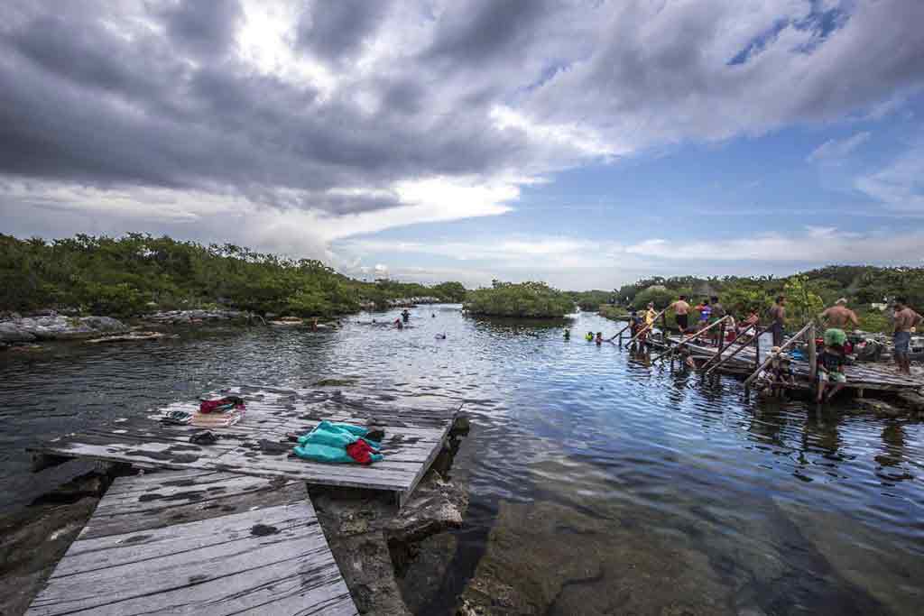 Yalku cenote surrounded by vegetation and people on the side